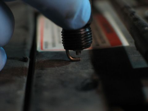 1994 Ford Bronco - Close-up of a spark plug being held by a gloved hand.