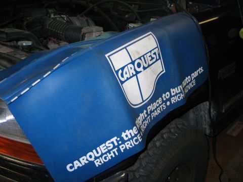 1994 Ford Bronco - A blue Carquest fender cover is placed over the engine bay of a vehicle.