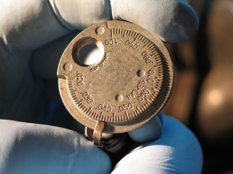 1994 Ford Bronco - Spark plug gap gauge with markings for inches and millimeters, used for setting spark plug gaps.