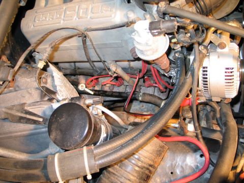 1994 Ford Bronco - Close-up view of an engine bay, showing spark plug wires, alternator, and oil filter. Visible text on the valve cover indicates '4.6L'.