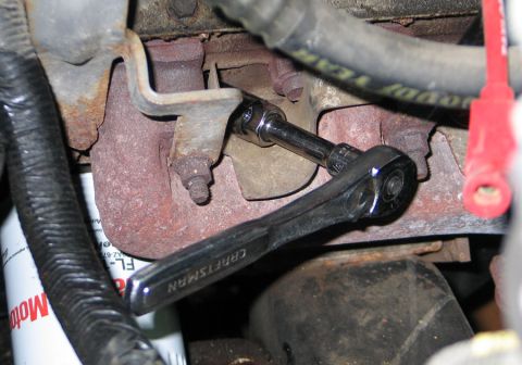 1994 Ford Bronco - Socket wrench being used on an engine part, with a spark plug wire nearby.