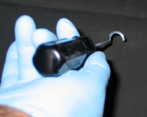 1994 Ford Bronco - A tool with a curved metal tip is held by a gloved hand against a dark background.