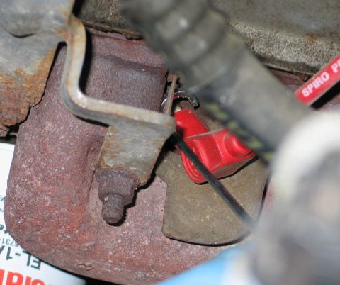 1994 Ford Bronco - Close-up view of a red spark plug wire connected to an engine part, with visible text on a label.
