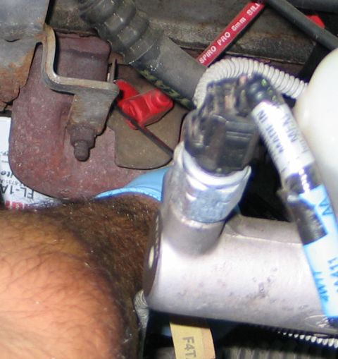 1994 Ford Bronco - Engine bay detail showing various components and a hand wearing a blue glove.