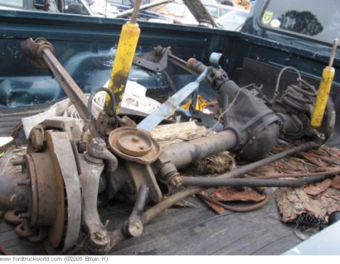 1974 Ford F-100 - Various truck suspension and axle components are piled in the bed of a pickup truck.