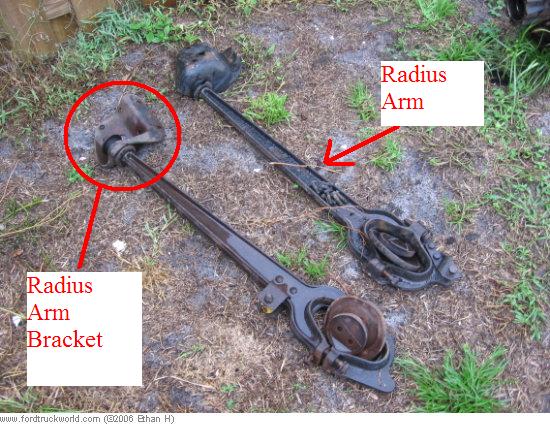 Two radius arms and their associated brackets lying on the ground