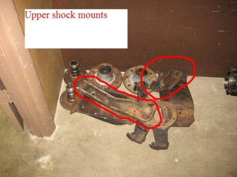 1974 Ford F-100 - Several rusty metal components, identified as upper shock mounts, are arranged on the floor.