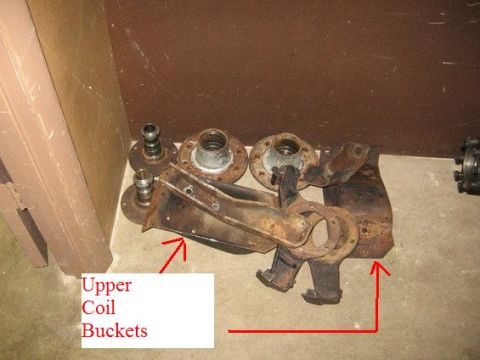 1974 Ford F-100 - Various rusty suspension components, including upper coil buckets, are laid out on a concrete floor.