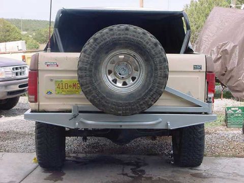 1990 Ford Bronco - Rear view of a beige SUV with a spare tire mounted on the back and an aftermarket bumper.