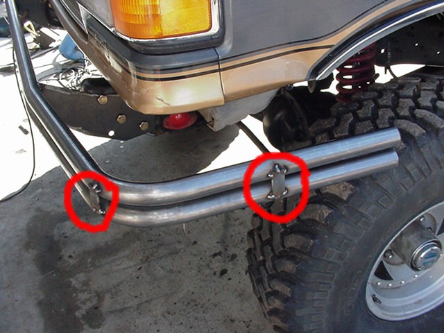 Bare tube bumper test-fit on gray Ford Bronco with red circles marking weld details