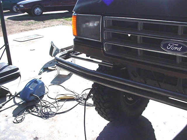 Low angle of bare two-tube bumper on lifted Ford truck below the Ford oval grille badge