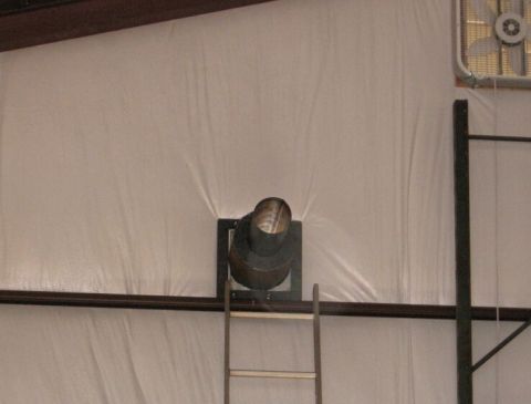1986 Ford Ranger - Interior view of a shop space, showing a ventilation pipe and a box fan mounted on the wall.