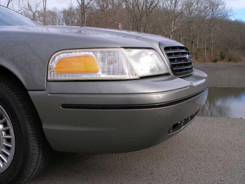 2001 Ford Crown Victoria - The front corner of a gray 2001 Ford Crown Victoria is visible, parked near a body of water.
