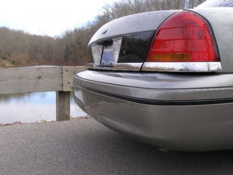 2001 Ford Crown Victoria - The rear of a gray sedan is shown parked next to a wooden railing with a body of water in the background.