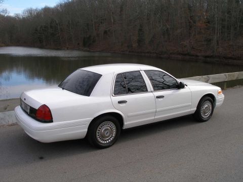 2001 Ford Crown Victoria - This white 2001 Ford Crown Victoria sedan is seen from a three-quarter front angle, parked near a body of water.