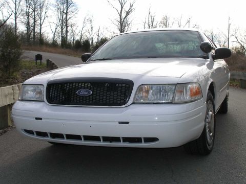 2001 Ford Crown Victoria - This white Ford Crown Victoria is parked outdoors with trees in the background.