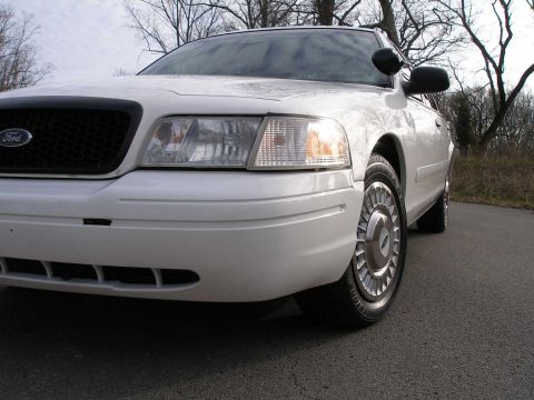 2001 Ford Crown Victoria - A white 2001 Ford Crown Victoria is shown from the front quarter angle on a paved road.