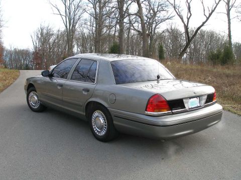 2001 Ford Crown Victoria - A 2001 Ford Crown Victoria is shown from the rear quarter angle on a tree-lined road.