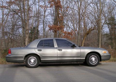 2001 Ford Crown Victoria - A silver 2001 Ford Crown Victoria is shown from the side, parked outdoors with bare trees behind it.