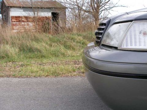 2001 Ford Crown Victoria - Front corner view of a gray 2001 Ford Crown Victoria, showing the grille and headlight assembly.