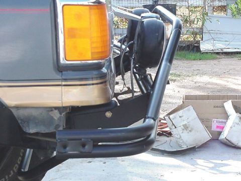 1988 Ford Bronco - Close-up view of a vehicle's rear bumper, a black brush guard and two auxiliary lights mounted on it.