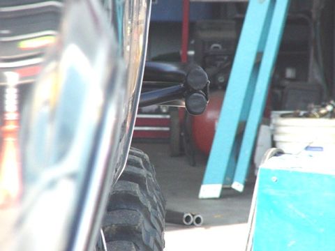 1988 Ford Bronco - A close-up view of a vehicle's chrome bumper and tire, with workshop equipment visible behind it.