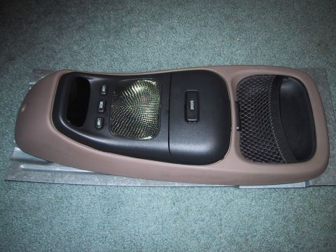 1994 Ford Bronco - Complete overhead console removed and laid face-up on green carpet, combining a tan outer shell with a dark gray center section holding a d…
