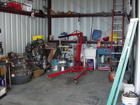 1988 Ford Bronco - A collection of engine parts and a red engine hoist are visible in a workshop setting.