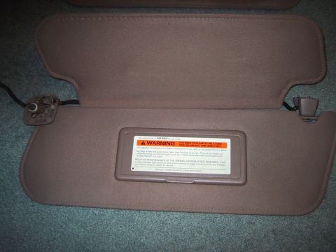1994 Ford Bronco - Two tan sun visors are shown, one with a prominent warning label regarding airbags and seatbelt usage.