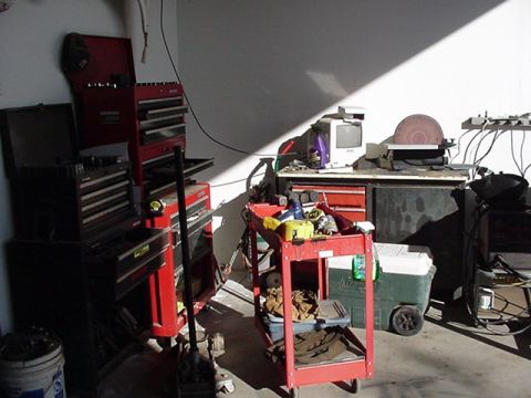 1988 Ford Bronco - A cluttered garage scene with various tools and equipment, including toolboxes and a disc sander.