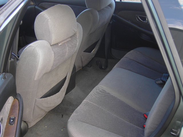 Gray cloth rear seat interior of a sedan with front seatbacks tilted forward