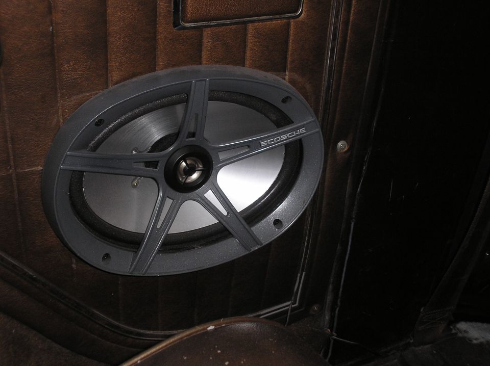 Close-up of a car's interior door panel with an oval speaker installed