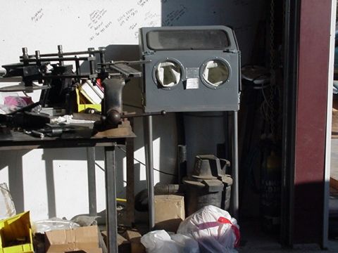 1988 Ford Bronco - A sandblaster cabinet sits on a stand in a workshop, surrounded by tools and supplies.