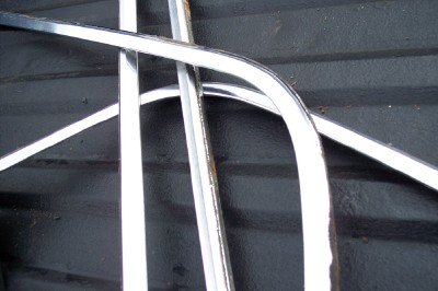 1972 Ford Ranchero - Close-up view of curved and straight chrome trim pieces, possibly for a vehicle restoration project.