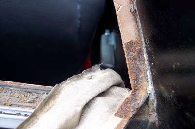 1972 Ford Ranchero - Close-up view of a corroded metal seam inside a vehicle, with a black seat visible.