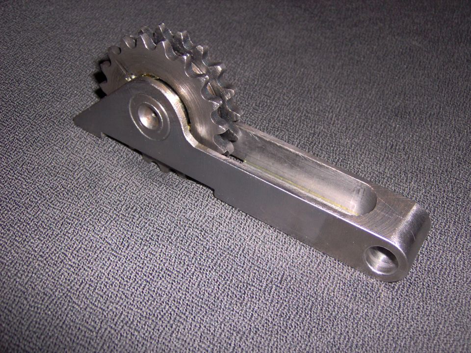Metal tensioner arm with double-row sprocket on gray fabric background
