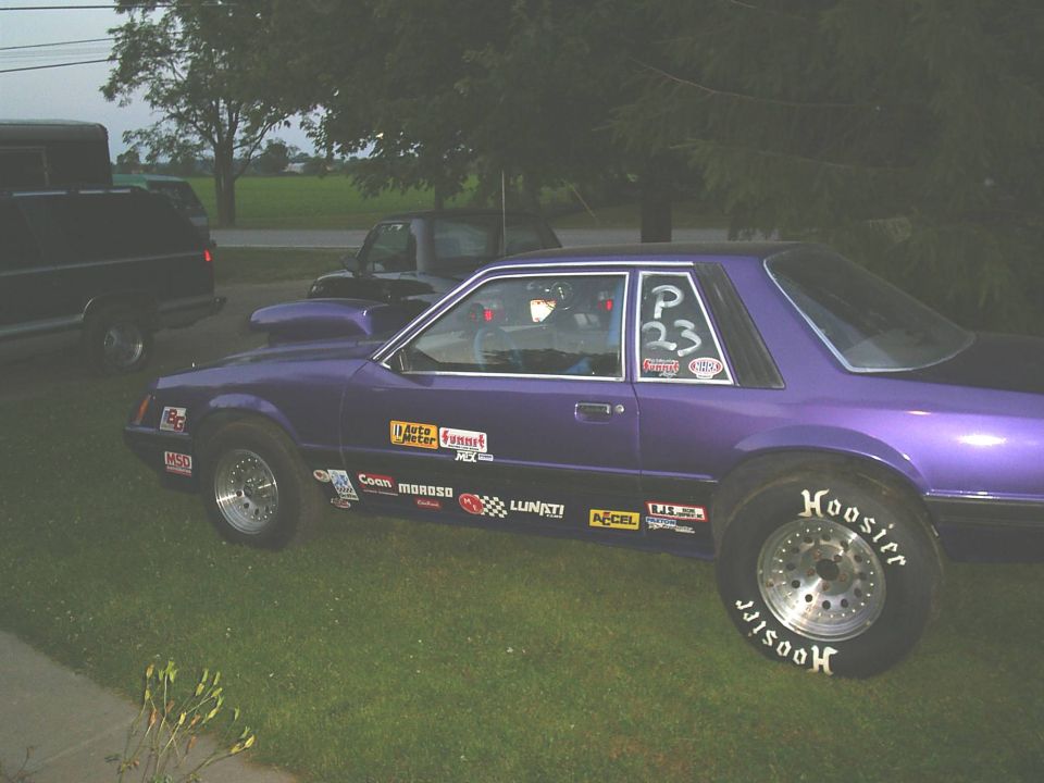 Purple Fox-body Mustang notchback drag car with Hoosier slicks and sponsor decals, side view on grass