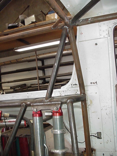 1988 Ford Bronco - A partially constructed tubular steel roll cage inside a vehicle body shell, showing bare metal tubing with visible welds and a triangulate…