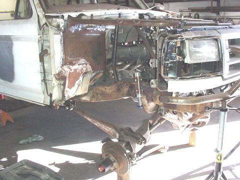 1988 Ford Bronco - A partially disassembled truck/SUV shot from the front passenger side, showing the exposed front suspension with control arms, brake hub, a…
