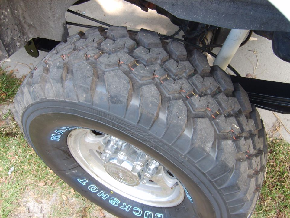 Close-up of a large off-road tire with 'BUCKSHOT' text and chrome hubcap