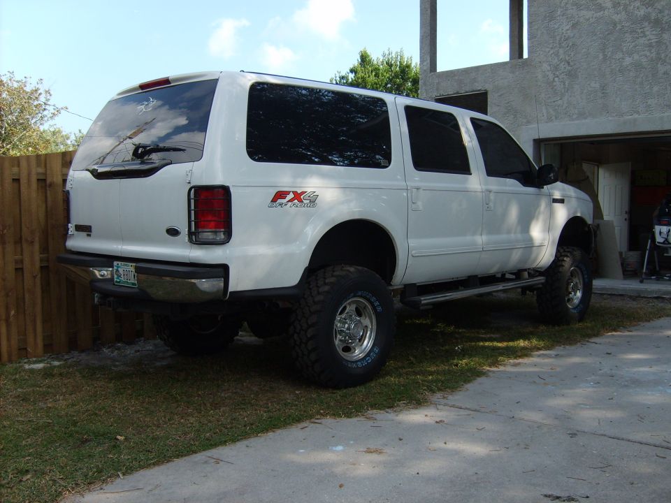 White Ford Excursion SUV, lifted, with FX4 Off-Road badging, seen from rear 3/4 angle