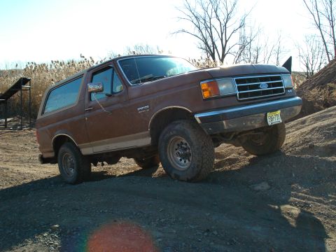 1990 Ford Bronco - This 1987 Ford Bronco is shown in a three-quarter front view, navigating a dirt terrain.