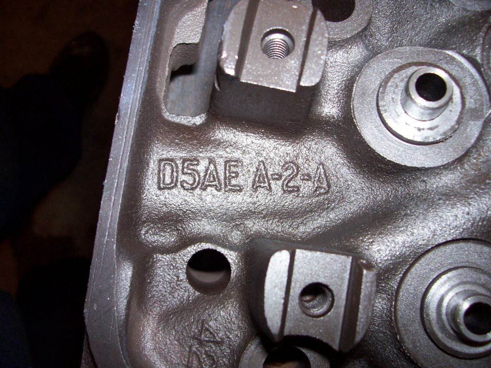 Close-up of a cast iron engine cylinder head with part number D5AE A-2-A stamped on it