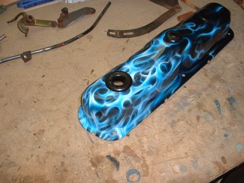 1978 Ford Mustang II - A custom-painted valve cover with a blue flame design sits on a workbench next to various engine components.