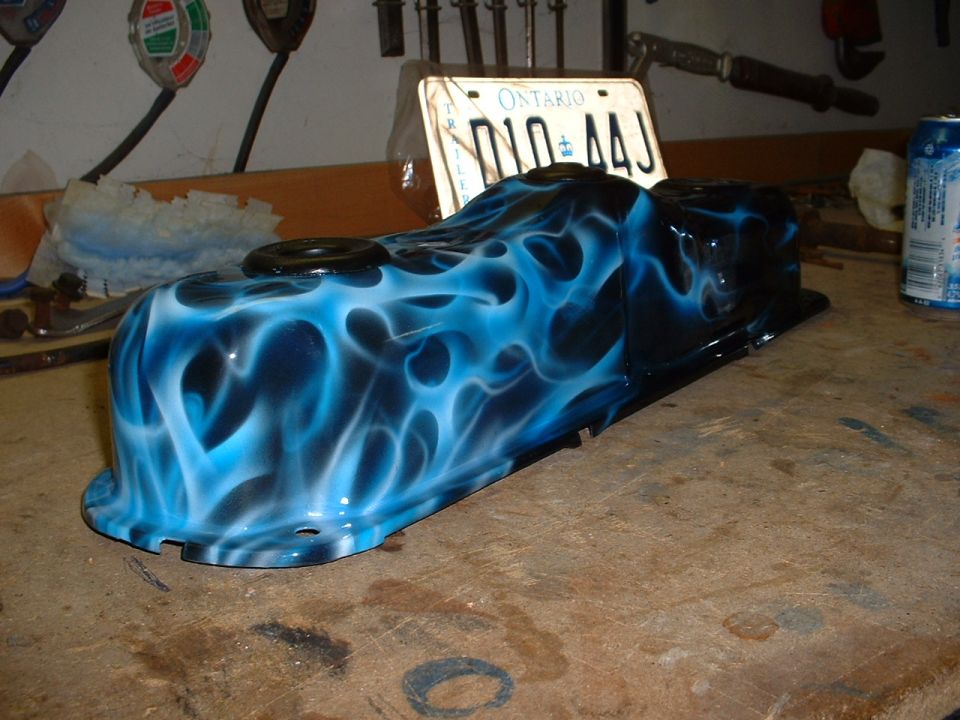 Blue flame airbrushed valve cover on workbench with license plate