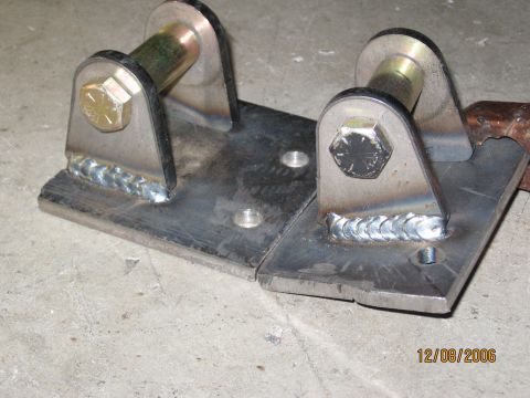 1994 Ford Bronco - Custom metal bracket with welded joints and bolt fasteners, photographed on a concrete floor.