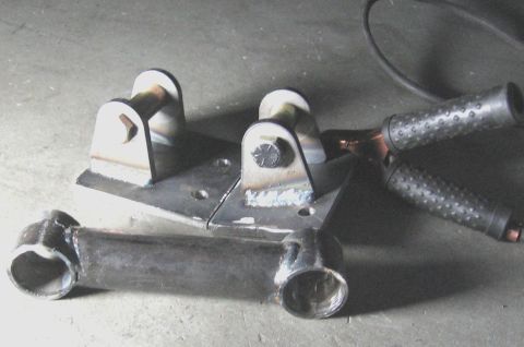 1994 Ford Bronco - Fabricated metal parts, possibly for a vehicle modification project, are shown on a concrete surface.