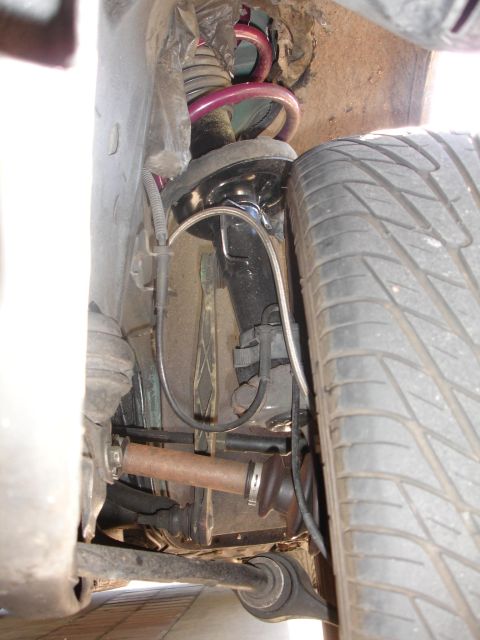 1993 Ford Taurus - This image shows the front suspension system of a vehicle, including the shock absorber, coil spring, and part of the wheel assembly.