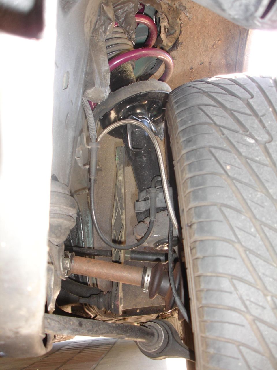 close-up of car's front suspension, shock, spring, and tire