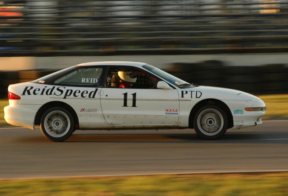 White ReidSpeed number 11 Ford Probe race car at speed, side view on track